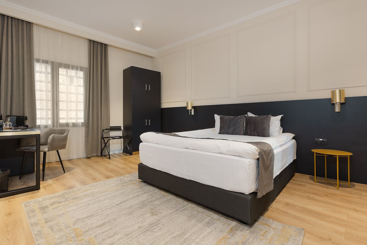A modern bedroom with a large bed, a desk, and a chair.