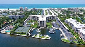Marina con barcos, cancha de tenis y un hotel de techo curvo.