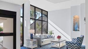 Un salón amplio con un gran ventanal, un sofá, una mesa de centro y un sillón estampado.