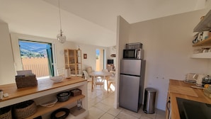 A modern kitchen with a built-in microwave, stainless steel refrigerator, and a wooden countertop. There is a dining area with a table and chairs visible through an open door. - Renovated T3 House in Collioure, 2 Bedrooms, Balcony (Collioure)