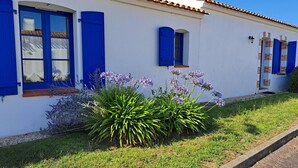 A white building with blue shutters and a tiled roof. - Beautiful villa with pool in quiet area in Saint-Jean-de-Monts (Saint-Jean-de-Monts)