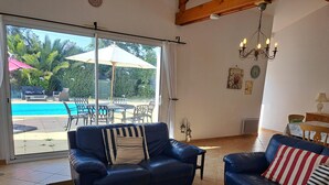A living room with a pool view, a wooden coffee table, and two sofas with striped cushions. - Beautiful villa with pool in quiet area in Saint-Jean-de-Monts (Saint-Jean-de-Monts)