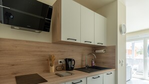 A modern kitchen with wooden countertops, a built-in stove, a sink, and white cabinets.