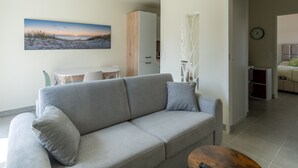 A modern living room with a grey sofa, a small table, and a painting of a beach scene.