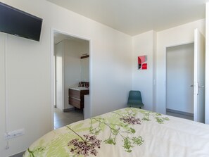 Ein Schlafzimmer mit Bett, Sessel, Fernseher und angrenzendem Badezimmer.