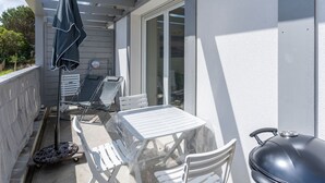A covered patio with a table and chairs, a grill, and a covered umbrella.