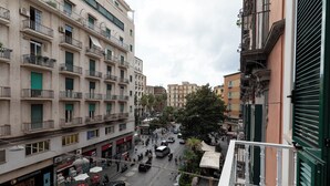 A multi-story building with balconies, a street with vehicles and pedestrians, and various storefronts. - Relais Ammira (Naples)