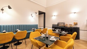 A modern dining area with yellow chairs, a blue sofa, and a buffet counter. - Relais Ammira (Naples)