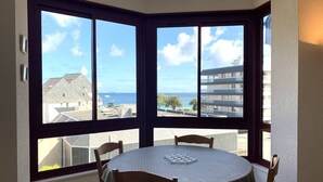 A corner room with a bay window overlooking a residential area and the sea.