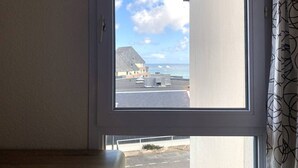 A window with a view of a building and the sea.