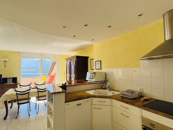 A kitchen with white cabinets, a microwave, and a sink. There is a dining area with chairs and a table.
