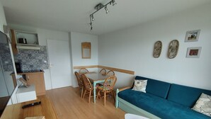 A compact living space with a dining area, a sofa, a small table, and a kitchenette.