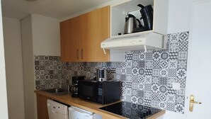 A compact kitchen with a microwave, coffee maker, and a small refrigerator.