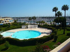 A pool surrounded by palm trees and a marina with numerous boats. - Beautiful 3-Room Apartment for 4 with Pool, Terrace, and Port View, 100m from Beach (Port Camargue)