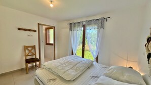 Une chambre à coucher avec un lit, une chaise, une fenêtre avec des rideaux et une porte.