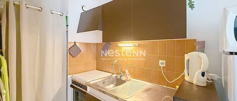 A compact kitchen with a sink, stove, and a small countertop.