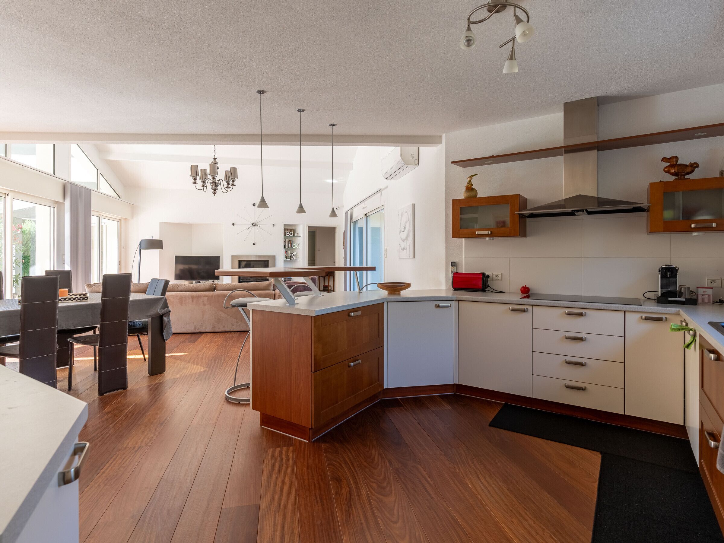 Una cocina moderna con armarios de madera, un comedor con sofá y sillas, y un ventanal que proporciona luz natural.