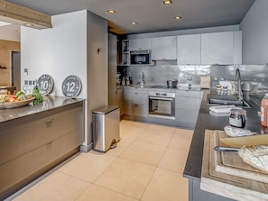 A modern kitchen with stainless steel appliances, a wooden countertop, and a trash bin.