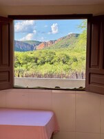 Una habitación con una cama y una ventana con vistas a un paisaje montañoso.