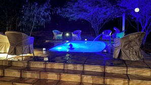A hot tub with a person in it, surrounded by chairs and a small table.
