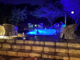 Un jacuzzi con una persona adentro, rodeado de sillas y una mesita.