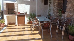 An outdoor patio with a brick oven, a table with chairs, and potted plants.
