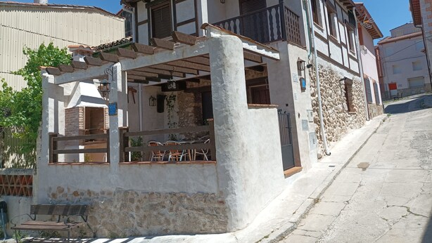 A two-story building with a balcony, a wooden bench, and a small outdoor seating area.