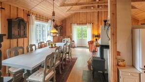 A wooden interior with a dining table, chairs, and a kitchen area with a stove. - Nice home in Folkestad with sauna (Folkestad)