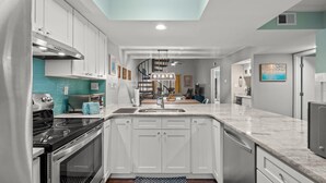 Une cuisine moderne avec des meubles blancs, une cuisinière noire et un îlot central doté d’un évier.