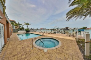 Un área de piscina con un jacuzzi, sillones de descanso y vistas al puerto deportivo.