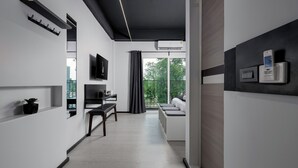 A modern interior with a minimalist design, featuring a flat-screen TV, a bench, and a seating area with a view of the outdoors. - BedTime Hotel Samui (Koh Samui)
