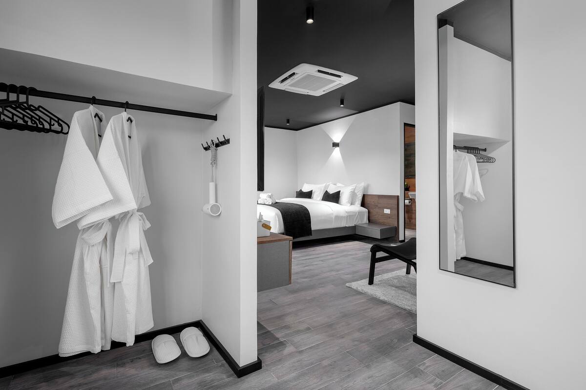 A modern hotel room with a bed, bedside table, and a large mirror.