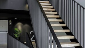 A modern staircase with a black railing and wooden steps, leading to an upper level. - BedTime Hotel Samui (Koh Samui)