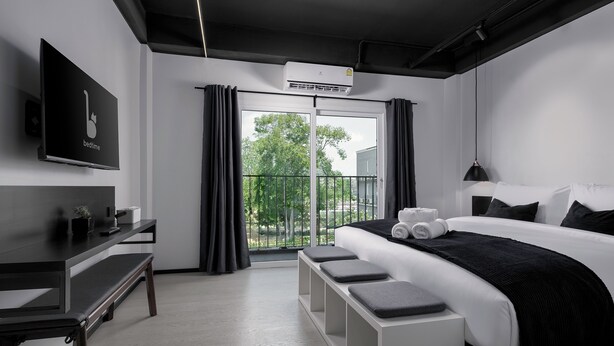 A modern hotel room with a large bed, a desk, a bench, and a TV. - BedTime Hotel Samui (Koh Samui)