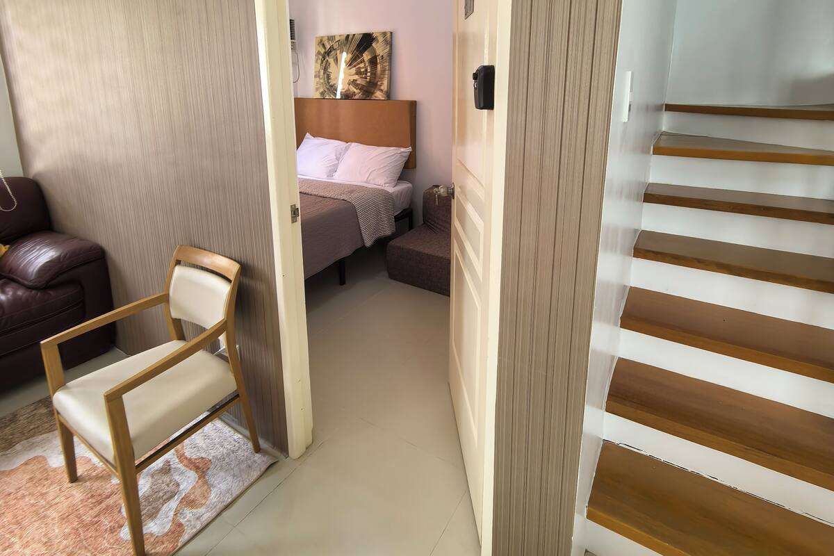 A hotel room with a bed, a chair, a sofa, and a staircase.
