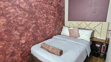 A bedroom with a bed, a nightstand, and a wall with a textured pattern.