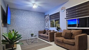 A modern living room with two sofas, a coffee table, a TV, and a ceiling fan.