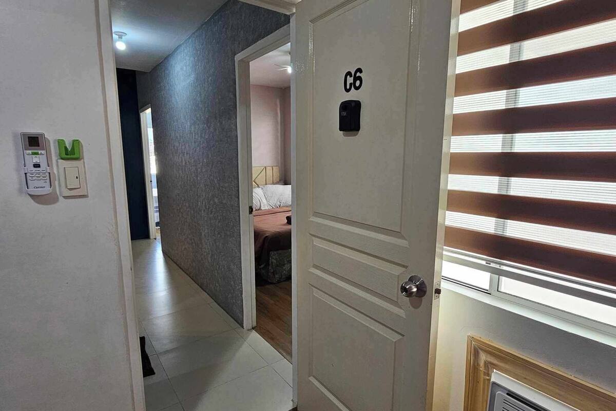 A hotel room with a door labeled 'C6', a bed, a radiator, and a window with blinds.