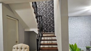A staircase with a modern design, a tufted armchair, and a potted plant.