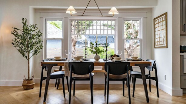 A dining area with a wooden table set for four, two black chairs, a potted plant, and a window with a view of a house. - Stunning-5 Bed-Close To Zoo, Balboa Park, Downtown (San Diego)