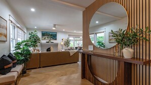 A modern reception area with a wooden reception desk, a large mirror, and a seating area with a sofa and chairs. - Stunning-5 Bed-Close To Zoo, Balboa Park, Downtown (San Diego)