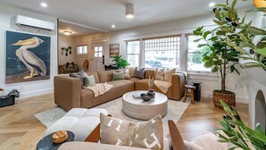 A modern living room with a sectional sofa, a round coffee table, and a large window with a view of the street. - Stunning-5 Bed-Close To Zoo, Balboa Park, Downtown (San Diego)