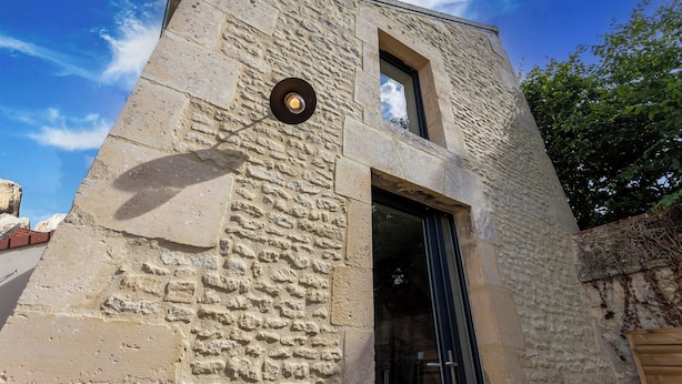 A stone building with a large window and a door.