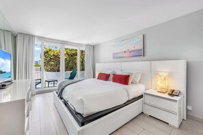 A modern hotel room with a bed, bedside table, and a view of the outdoors. - Poolside Escape with Hot Tub Access | StayCozy (Miami)