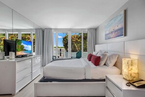 A modern hotel room with a large bed, a television, a desk, and a view of the outdoors. - Poolside Escape with Hot Tub Access | StayCozy (Miami)