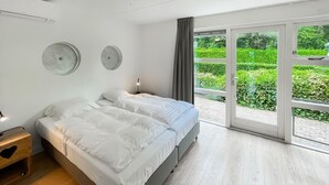 A modern bedroom with a large bed, a bedside table, and a view of greenery through the sliding glass door. - 3 bedroom stunning home in Workum (Workum)