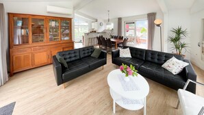A spacious living room with two black leather sofas, a wooden cabinet, and a white coffee table with flowers. - 3 bedroom stunning home in Workum (Workum)