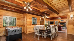 A wooden interior with a dining table, chairs, a foosball table, and a fireplace. - Black Diamond | Family & Pet-Friendly Cabin Near Huntington Lake (Big Creek)