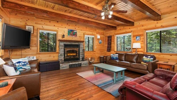 A log cabin interior with a fireplace, leather furniture, and a television. - Black Diamond | Family & Pet-Friendly Cabin Near Huntington Lake (Big Creek)