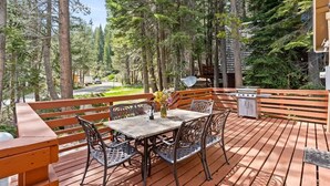 A wooden deck with a table and chairs, surrounded by trees. - Black Diamond | Family & Pet-Friendly Cabin Near Huntington Lake (Big Creek)